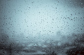 Rain drops on window glass outside texture background water of wonderful heavy rainy day with sky clouds at city blue green blurred lights abstract view sunshine enjoy the relaxing nature wallpaper