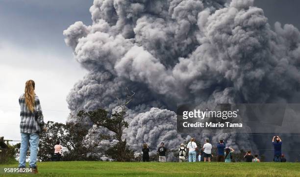 People watch at a golf course as an ash plume rises in the distance from the Kilauea volcano on Hawaii's Big Island on May 15, 2018 in Hawaii...