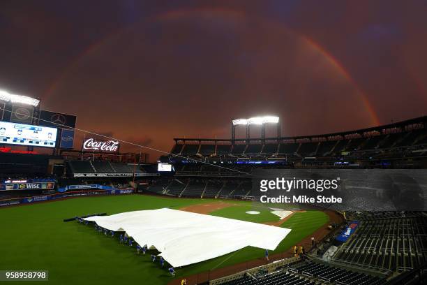 Rainbow is seen as the grounds crew removes the tarp prior to the start of the game between the New York Mets and the Toronto Blue Jays at Citi Field...