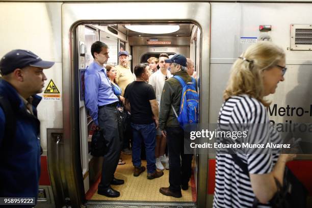 Commuters board trains as they wait for train service to be restored after a severe thunderstorm downed trees that caused power outages resulting in...