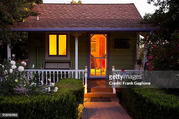 cottage with a woman inside at dusk. - charming stockfoto's en -beelden