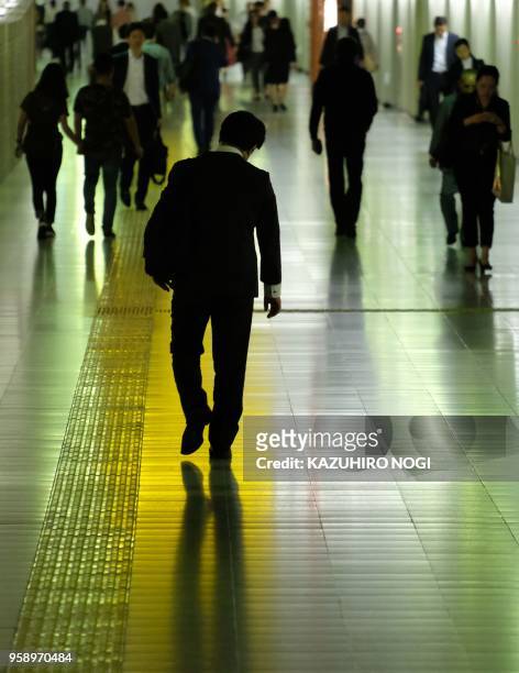 This picture taken on May 15, 2018 shows passerby walking on a concourse at a railway station in Tokyo. - Japan's economy shrank for the first time...