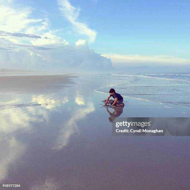 little boy playing in the sand at  sunset - boy exploring on beach stock-fotos und bilder