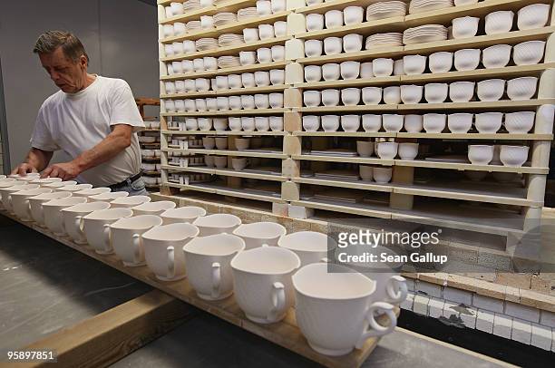 An artisan removes porcelain cups from wooden pallets after kilning at the manufactury of German luxury porcelain maker Meissen on January 20, 2010...