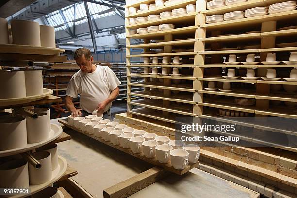 An artisan removes porcelain cups from wooden pallets after kilning at the manufactury of German luxury porcelain maker Meissen on January 20, 2010...