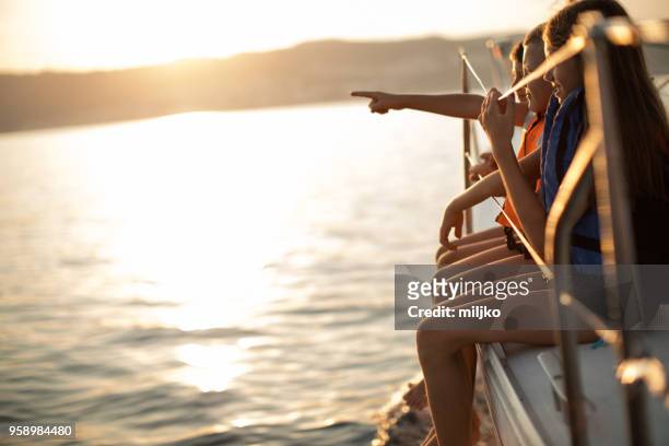 children sitting on sailboat deck while sailing - miljko stock pictures, royalty-free photos & images