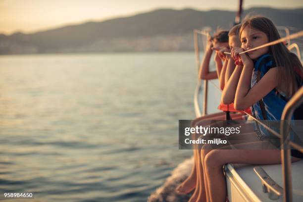 children sitting on sailboat deck while sailing - miljko stock pictures, royalty-free photos & images