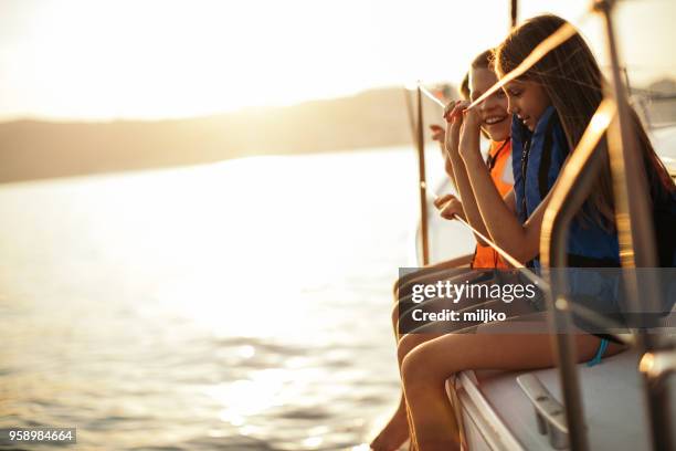 children sitting on sailboat deck while sailing - miljko stock pictures, royalty-free photos & images