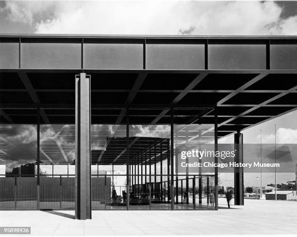 Exterior view of the New National Gallery in Berlin , showing glass walls and overhang, looking at interior, with reflections on glass walls of sky...