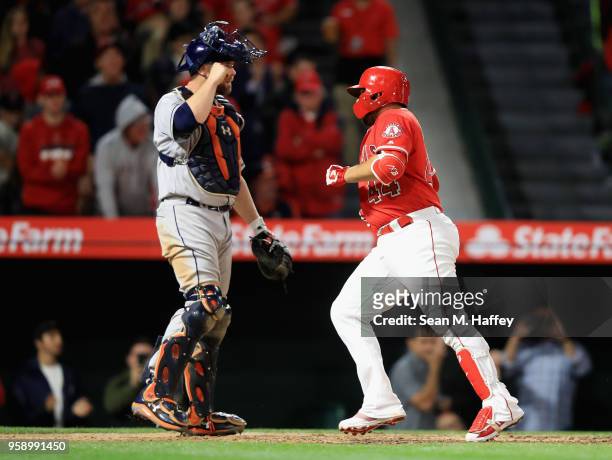 Rene Rivera of the Los Angeles Angels of Anaheim touches home plate after hitting a solo homerun as Brian McCann of the Houston Astros looks on...