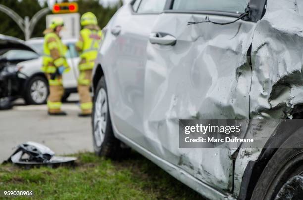 close up on a car crashed with fireman in background - motor vehicle crash stock pictures, royalty-free photos & images