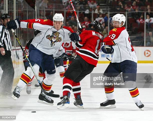 Bryan Allen and Dominic Moore of the Florida Panthers hit Dean McAmmond of the New Jersey Devils during the game at the Prudential Center on January...