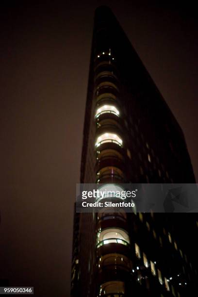 looking up at partially illuminated flat iron building at night - silentfoto stock-fotos und bilder