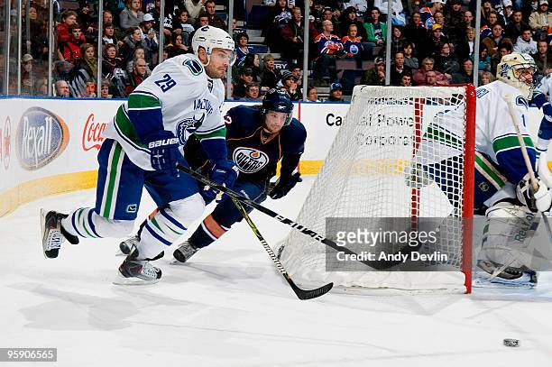 Robert Nilsson of the Edmonton Oilers and Aaron Rome of the Vancouver Canucks go for the puck as goalie Roberto Luongo follows the action from the...