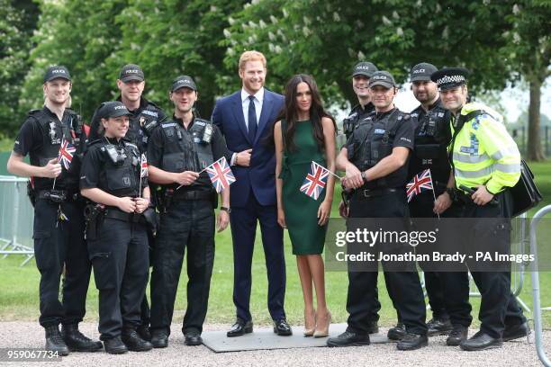 Police officers poses for photos with the Madame Tussauds' wax figures of Prince Harry and Meghan Markle as they are paraded along the Long Walk in...