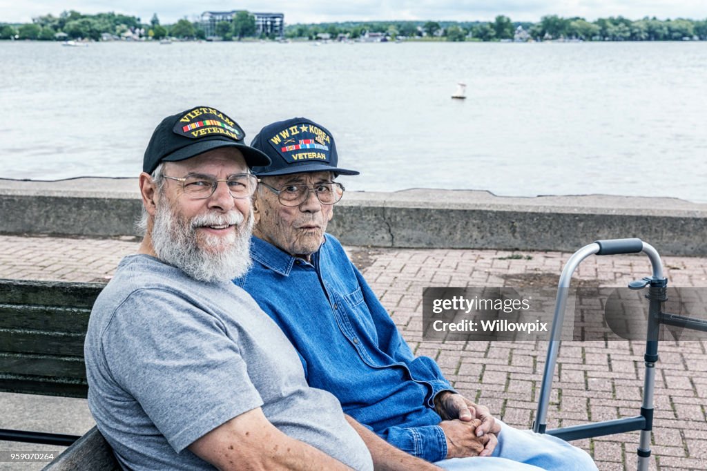 Dos generaciones de veteranos militares de los E.e.u.u. adultos Senior sentado en el lago