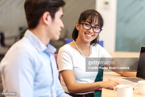 young asian man and woman on a business meeting in an office looking at each other - タギグ ストックフォトと画像
