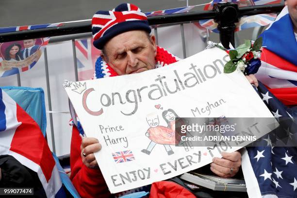 Royal fan Terry Hutt holds a placard as he sits on a street corner along the Wedding procession route to secure his viewing spots for the Wedding...