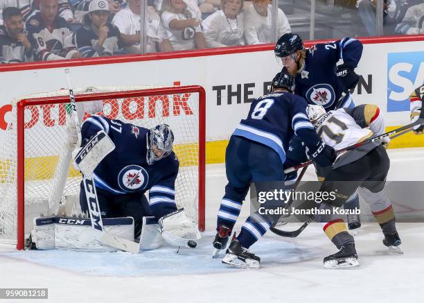 Goaltender Connor Hellebuyck of the Winnipeg Jets catches the puck in the crease as teammates Patrik Laine and Jacob Trouba defend against William...