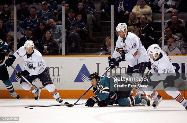 Ryane Clowe of the San Jose Sharks reaches for the puck as is he surrounded by Robert Nilsson, Ethan Moreau and Lubomir Visnovsky of the Edmonton...