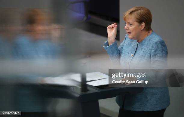 German Chancellor and leader of the German Christian Democrats Angela Merkel is reflected in glass as she addresses the Bundestag during debates over...