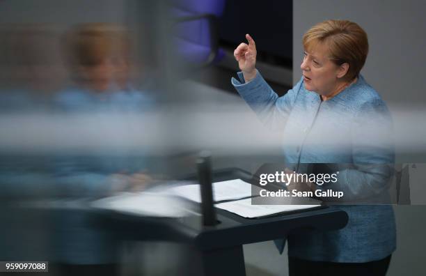 German Chancellor and leader of the German Christian Democrats Angela Merkel is reflected in glass as she addresses the Bundestag during debates over...