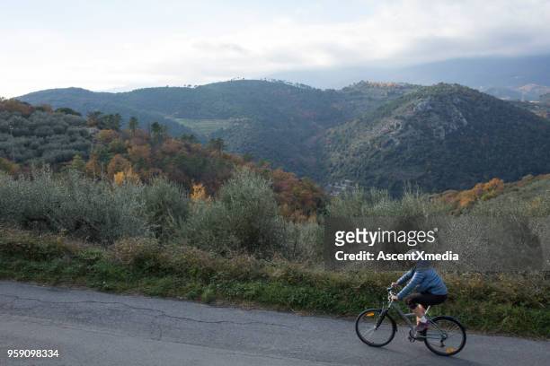 woman bikes above olive grove and mountains - wellness olive tree stock pictures, royalty-free photos & images