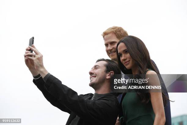 Visitor takes a selfie photograph with waxwork figures of Britain's Prince Harry and his US fiance Meghan Markle, during a photo oportunity arranged...