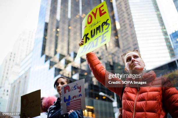 Woman holds a placard reading "Love Still Trumps Hate" outside Trump Tower on 5th Avenue in Midtown Manhattan two days after America's vote as...