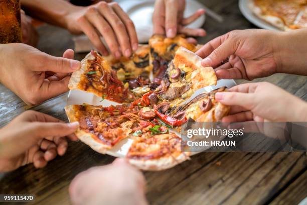 close up image of friends having pizza at bar - pizza restaurant stock pictures, royalty-free photos & images