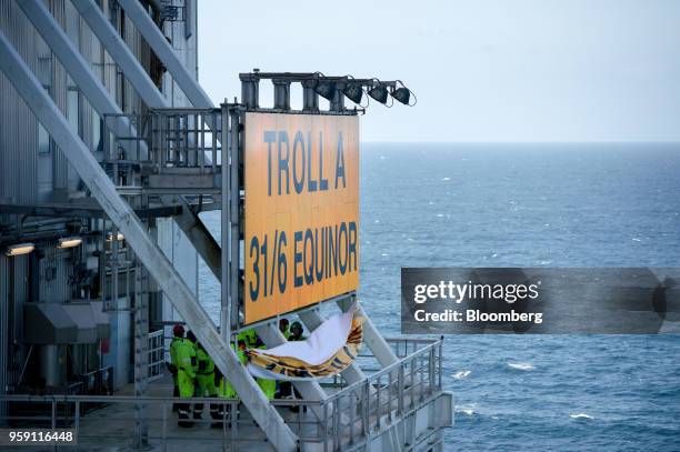 Workers unveil the new Equinor name on the Troll A natural gas platform, operated by Equinor ASA, in the North Sea, Norway, on Wednesday, May 16,...