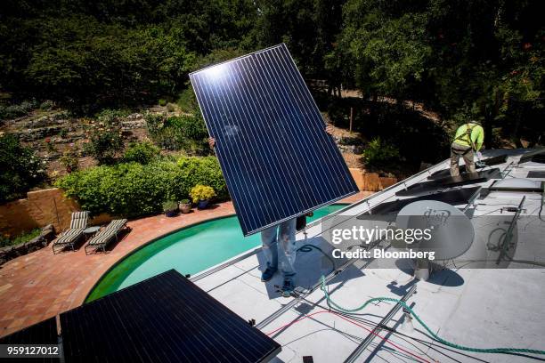 PetersenDean Inc. Employees install solar panels on the roof of a home in Lafayette, California, U.S., on Tuesday, May 15, 2018. California became...