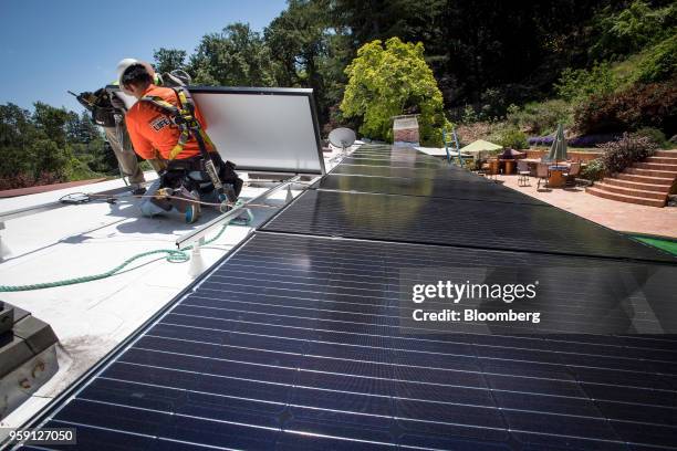 PetersenDean Inc. Employees install solar panels on the roof of a home in Lafayette, California, U.S., on Tuesday, May 15, 2018. California became...