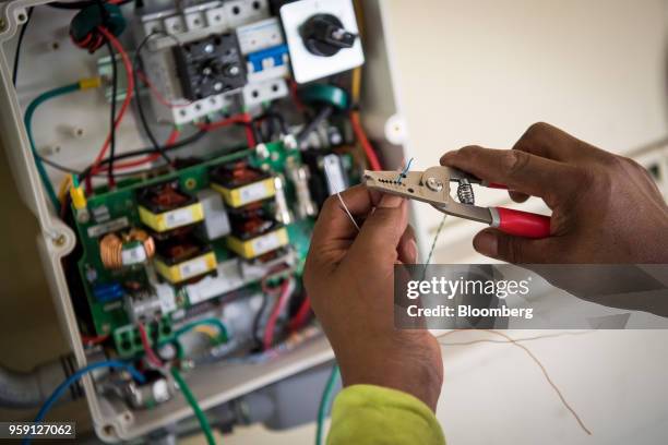 PetersenDean Inc. Employee installs wiring for a solar inverter on a home in Lafayette, California, U.S., on Tuesday, May 15, 2018. California became...