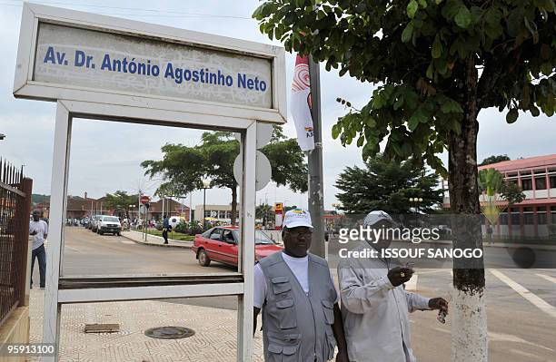 Two men stand on the Avenue Dr Antonio Agostinho Neto of the 2010 African Cup of Nations football tournament near a building on January 20, 2010 in...