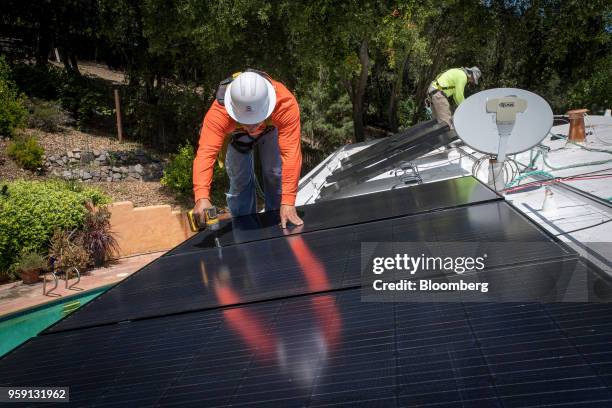 PetersenDean Inc. Employees install solar panels on the roof of a home in Lafayette, California, U.S., on Tuesday, May 15, 2018. California became...