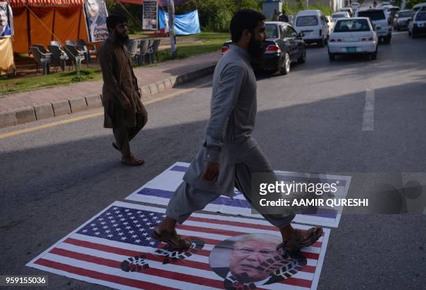 Pakistani man walks over the US and Israeli flags bearing with the images of US President Donald Trump and Israeli Prime Minister Benjamin Netanyahu...