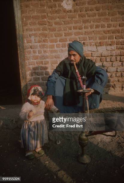 An Egyptian man with his daughter smoking a hookah.