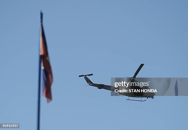 Helicopter flies past the Hatian flag January 21, 2010 in Leogane, Haiti. The United States is now operating at four airports to ferry aid and relief...