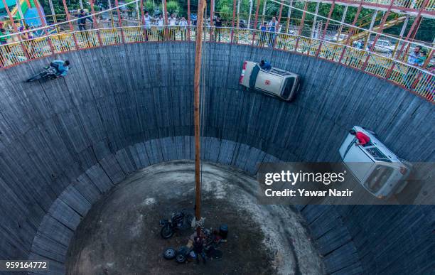 Stunt drivers and motorcyclist daredevils perform in the well of death on May 15, 2018 in Srinagar, the summer capital of Indian administered...