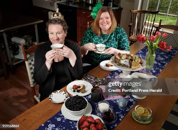 Karen Sigler, left, wearing a crown, and Kristin Fuhrmann-Simmons, wearing a fascinator, pose for a photo with some of the types of food and tea that...