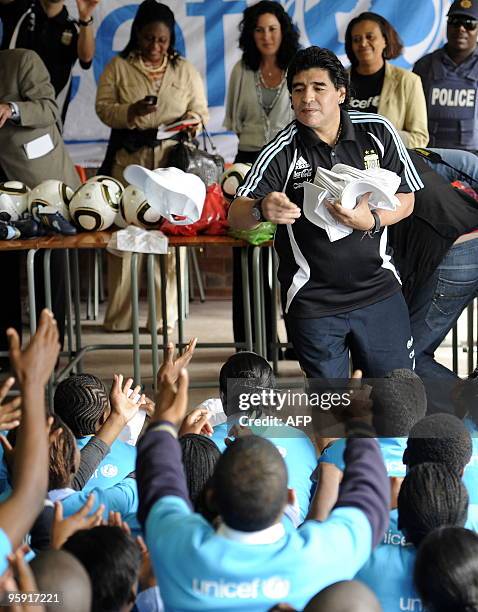 Argentinian football coach Diego Maradona distributes caps to students during a visit to Selekelela Secondary School on January 21, 2010 in Soweto on...