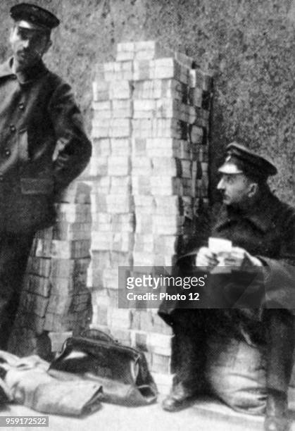 Germany; Men sitting in front of piles of worthless money during the inflation.