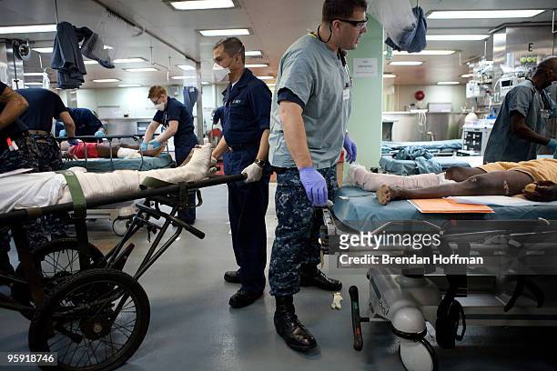 Naval medical staff treat Haitian earthquake victims, both with suspected fractured femurs, in the casualty receiving area of the USNS Comfort, a...