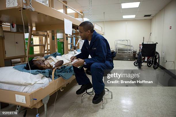 Ernsley Victome, an English/Creole translator, talks with a 12-year-old girl who broke her leg when a wall fell on her during the earthquake in the...