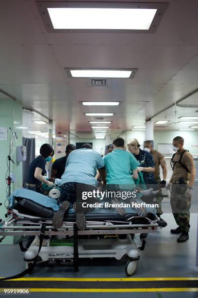 Doctors move a newly-arrived Haitian earthquake victim from a stretcher to a gurney in the casualty receiving area on board the USNS Comfort, a U.S....