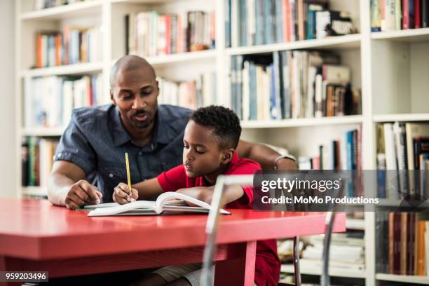 father helping son with homework - half shaved hairstyle stock-fotos und bilder