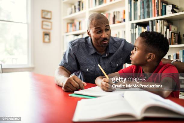 father helping son with homework - incoraggiamento foto e immagini stock