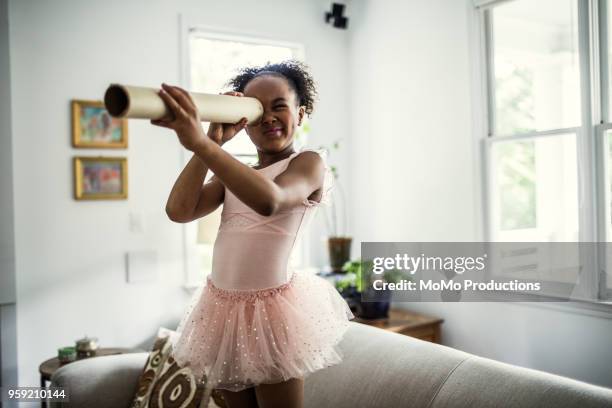 young girl looking through homemade telescope at home - entertainment occupation stockfoto's en -beelden