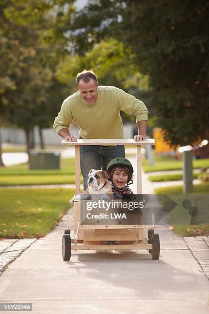 father pushing son and puppy in soap box car - soapbox cart foto e immagini stock